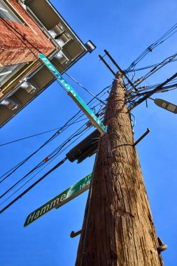 Cincinnati 'nin Ren Bölgesi' ndeki ahşap elektrik direğinde Benton ve Hammer Caddesi 'nin dramatik manzarası. Açık mavi gökyüzü ve şehir elementleri bir bağlantı ve şehir hayatı manzarası yaratır..