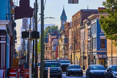 Ren Bölgesi üzerindeki Cincinnati kentsel sokak sahnesinde renkli tarihi tuğla binalar, hareketli şehir hayatı ve klasik saat kulesinin arka planıyla mimari cazibe ön plana çıkıyor..