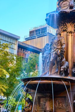 Ohio, Cincinnati Fountain Meydanı 'ndaki Bronz Çeşme' de çelenk ve köpeği olan bir adam var. Modern mimari ile çevrelenmiş olan sahne, tarih ve şehir yaşamının altın saatinde sakin bir karışımını yakalıyor..