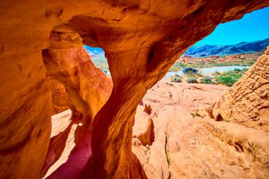 Nevada 'daki Fire State Park Vadisi' nde canlı bir çöl manzarası. Göz kamaştırıcı kumtaşı oluşumlarını ve parlak mavi gökyüzünün altındaki doğal kemerleri keşfedin. Macera ve doğa yolculuğu temaları için mükemmel..
