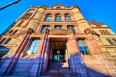 Sunlit Cincinnati City Hall stands majestically in Romanesque Revival style. The grand entrance and flagpole reflect civic pride and heritage, perfect for highlighting historic architecture and clipart