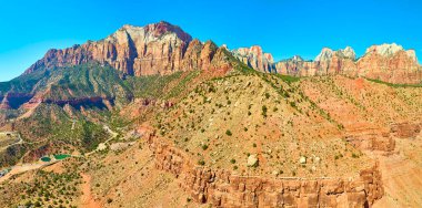 Utah 'taki Zion Ulusal Parkı' nın nefes kesici güzelliğini keşfedin. Kum taşı kayalıklarının ihtişamını, açık mavi bir gökyüzünün altında, havadan görüntülenerek yaşayın. Macera ve seyahat için mükemmel.