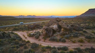 Utah Kasırgası 'nda yalnız bir araba Gooseberry Mesa' dan geçerken, sakin bir çöl. Macera dolu keşiflerin ve yalnızlığın ruhunu büyüleyici bir günbatımı arkaplanına yansıt..