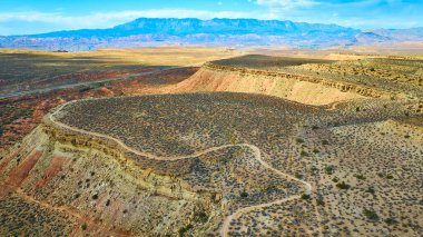 Utah Kasırgası 'ndaki Bektaşi üzümü Mesa' sının çarpıcı güzelliğini keşfedin. Bu hava manzarası engebeli çöl manzarasını, dolambaçlı yolları ve öğleden sonra ışıklarıyla görkemli dağ zeminini yakalar..