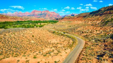 Grafton Utah 'ın hava manzarası mavi gökyüzünün altındaki çarpıcı kızıl kayalıkları gösteriyor. Bereketli yeşil bir vadi çöl arazisine zıt düşüyor. Bu ikonik Amerikan güneybatısının dolambaçlı yolu boyunca maceraya davetiye çıkarıyor.
