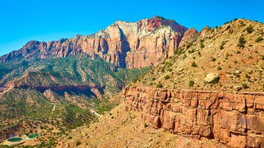 Springdale Utah yakınlarındaki Zion Ulusal Parkı 'nın görkemli kızıl kaya kayalıkları. Bu dolambaçlı yol, Güneybatının engebeli güzelliğini ve macerasını yakalayan canlı mavi gökyüzü altında keşfe davet ediyor..