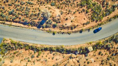 Utah 'ın uçsuz bucaksız çöllerinde dolambaçlı bir yolda giden yalnız bir arabanın hava görüntüsü. Canlı toprak tonları özgürlük ve keşfi çağrıştırırken yalnızlığı ve macerayı tecrübe edin. Yolculuk için mükemmel.