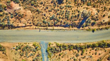 Grafton Utah 'ın çorak arazisini kesen ıssız bir yolun havadan görünüşü. Altın saat ışığı engebeli arazide dramatik gölgeler oluşturuyor. Çöl yalnızlığının güzelliğini vurguluyor..