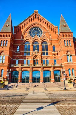 Cincinnati Müzik Salonu 'nun tarihsel ihtişamı: kırmızı tuğlalı ve çarpıcı vitray pencereli Gotik Diriliş başyapıtı, Ohios kentsel manzarasında açık mavi bir gökyüzüne karşı kurulmuş..
