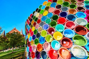 Canlı boya kutuları, Cincinnati Washington Parkı 'ndaki tarihi kırmızı tuğla zemine karşı renkli bir yapı oluşturuyor, yaratıcılığı, çeşitliliği ve kentsel sanatsal ifadeyi simgeliyor..