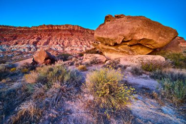 Günışığı kayası, Utah, Gooseberry Mesa 'da mavi gökyüzüne karşı görkemli bir şekilde duruyor. Katmanlı uçurumlar ve seyrek çöl bitkileri bu çarpıcı manzaranın ebedi güzelliğini ve dayanıklılığını vurgular..