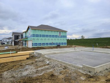 Fort Wayne 'deki banliyö genişlemesi: Sabahın erken saatlerinde iki katlı bir inşaat sahasında, yeşil renkte hava geçirmez, dingin bir büyüme ve gelişmeyi gösteren