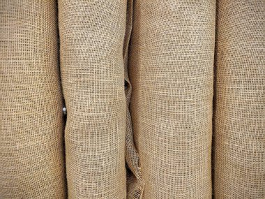 Coarse burlap rolls stacked in a Fort Wayne warehouse showcase eco-friendly texture. Ideal for sustainable projects and rustic designs highlighting durability and natural beauty. clipart