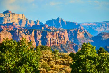 Experience the majestic beauty of Kolob Canyon at Zion National Park. Towering red sandstone cliffs glow in golden hour light, surrounded by lush greenery in the heart of Utah stunning landscape. clipart