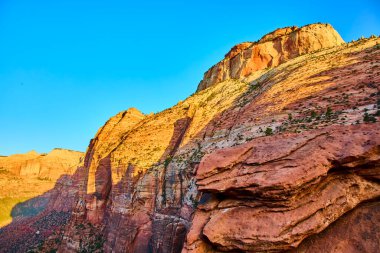 Zion Ulusal Parkı 'ndaki altın saat Pine Creek Kanyonu' nun canlı kırmızı ve turuncu kumtaşı uçurumlarını gözler önüne seriyor. Utahların ikonik manzaralarının engebeli güzelliğini ve dingin görkemini tecrübe edin..