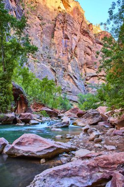 Serene nehri Zion Ulusal Parkı 'ndan akar görkemli kırmızı kaya kanyonları altın saatinde. Yeşillik ve turkuaz sular Utah 'ta büyüleyici bir keşif ve doğal güzellik manzarası yaratır..