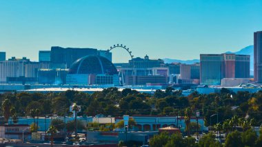 Las Vegas 'ın havadan görünüşü modern Küre' yi ve ikonik dönme dolabı canlı bir siluet üzerinde yakalar. Bu dinamik şehir manzarası, parlak mavi gökyüzü altında klasik kumarhane cazibesiyle buluşları harmanlıyor..