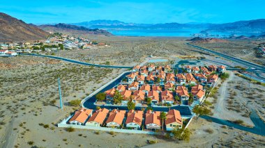 Nevada 'nın Boulder City banliyösünün hava manzarasında planlanan kırmızı çatılı evler, çöl arazisi ve yakınlardaki Mead Gölü' nün berrak gökyüzünün altında ferahlatıcı mavi bir alan sergileniyor..
