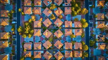 Golden hour aerial view of a Las Vegas suburban neighborhood. Symmetrical grid layout with terracotta roofs, greenery, and parked cars. Perfect for urban planning or real estate themes. clipart