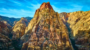 Nevada 'daki Red Rock Kanyonu' nun çarpıcı güzelliğini keşfedin. Bu hava görüntüsü parlak mavi gökyüzü altında canlı kırmızı ve bej kaya oluşumlarını yakalar. Macera ve keşif temaları için mükemmeldir..