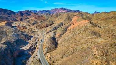 Nevada 'daki Nelsons Landing' in engebeli çöl manzarasında dolambaçlı bir yol manzarası. Uçsuz bucaksız arazi, geniş mavi gökyüzünün altında macera ve yalnızlığı davet ediyor. Seyahat için ideal.