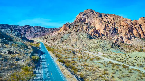 Nelson, Nevada 'nın engebeli güzelliğini yukarıdan keşfedin. Bu büyüleyici çöl manzarasının içinden geçen dolambaçlı bir yol macera, yalnızlık ve doğal ihtişam temaları için mükemmel..