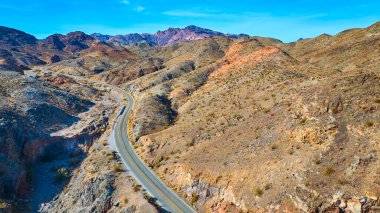 Nelsons Landing yakınlarında Nevadas 'ın engebeli çölünden geçen virajlı bir yolun havadan görüntüsü. Güneşli tepeler ve dağ manzarası macera ve el değmemiş vahşi doğanın güzelliğini çağrıştırıyor. Seyahat temaları için ideal.