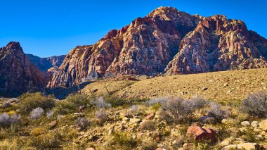 Las Vegas, Nevada yakınlarındaki Red Rock Kanyonu 'nun havadan görüntüsü. Yüksek kırmızı kaya oluşumları parlak mavi gökyüzü ile tezat oluşturarak Pine Creek Kanyonları 'nın engebeli çöl manzarasının görkemli güzelliğini yakalıyor..