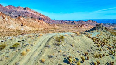 Nelson 'ın hava manzarası, Nevadas' ın engebeli çöl manzarası. Toprak bir yol, canlı mavi bir gökyüzünün altında kayalıkların arasından esiyor. Bu sakin vahşi doğada macera ve keşiflere davetiye çıkarıyor..