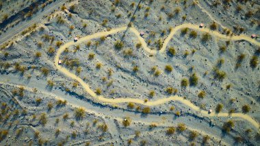 Aerial view of a winding dirt path through the serene desert landscape near Boulder City Nevada. Warm golden light highlights the rugged terrain creating a sense of adventure and tranquility. clipart