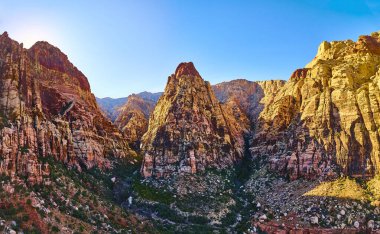 Nevada 'daki Sunlit Red Rock Kanyonu' nda altın saat boyunca yüksek tepeler ve canlı renkler sergileniyor. Bu nefes kesici manzara, Las Vegas yakınlarındaki sakin çöl güzelliğini keşfetmeye davet ediyor..