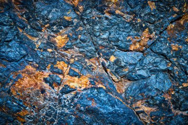 Nevada, Boulder City 'deki Bootleg Canyon' un engebeli güzelliğini keşfedin. Kayalık bir yüzeyin bu yakın çekiminde canlı mavi ve paslı turuncu renkler, karmaşık desenler ve dokular ortaya çıkar..