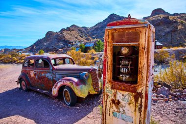 Abandoned vintage car and rusted gas pump in Nelson, Nevada ghost town. A haunting scene of decay under a bright blue sky evokes nostalgia and the rich history of the American Southwest. clipart