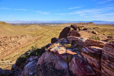 Kraft Dağı yakınlarındaki kırmızı kaya oluşumlarıyla dolu canlı çöl manzarası Nevada 'daki doğa ve kentsel yaşam arasındaki zıtlığı gözler önüne sererek Las Vegas ufuk çizgisini çarpıcı bir şekilde gösteriyor..