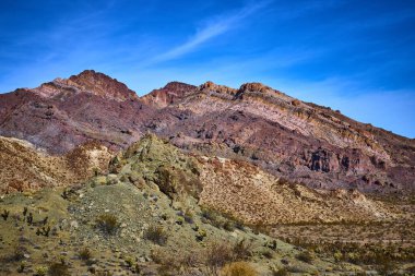 Nevada, Boulder City 'deki Bootleg Canyon' un el değmemiş el değmemiş doğasını deneyin. Bu çarpıcı çöl dağ manzarasında parlak mavi gökyüzü altında canlı renklere ve engebeli kaya oluşumlarına hayret edin..