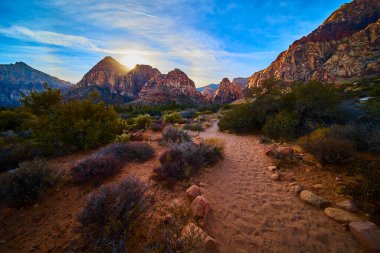 Gün batımında Red Rock Kanyonu 'nun dingin güzelliğini keşfedin. Altın parıltı, bu Nevada çölünün engebeli dağlarını ve kumlu patikalarını vurguluyor. Macera ve keşif için mükemmel..