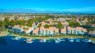 Aerial view of a serene Las Vegas suburb with terracotta-tiled waterfront homes along a tranquil canal. Enjoy modern living amid lush greenery and mountains in a well-planned Nevada community. clipart