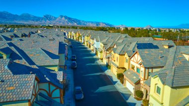 Dünya tonlu evleri ve güneş panelleri olan sakin bir Las Vegas banliyö mahallesinin havadan görünüşü. Engebeli dağlar ve berrak gökyüzü bu güzel çöl manzarasında sürdürülebilir yaşamın altını çiziyor..