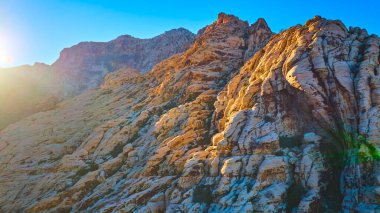 Altın saat, Nevada 'daki Red Rock Kanyonu' nun dokulu kumtaşı kayalıklarına sıcak bir ışık saçıyor. Bu nefes kesici hava manzarası Las Vegas yakınlarındaki engebeli güzelliği ve dingin atmosferi yakalıyor..