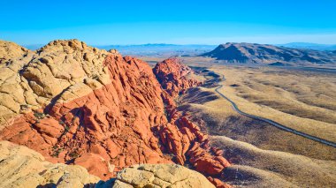 Las Vegas, Nevada yakınlarındaki Red Rock Kanyonu 'nun üzerinde canlı kumtaşı oluşumları ve geniş çöl manzarasıyla süzülür. Dolambaçlı bir yol bu nefes kesici hava sahnesinde macera ve keşfe davet ediyor..