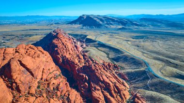 Nevada 'daki Red Rock Kanyonu' nun canlı kırmızı kumtaşını yukarıdan deneyin. Bu çarpıcı hava manzarası, açık mavi gökyüzünün altında Las Vegas yakınlarında engebeli güzelliği ve engin genişliği yakalıyor..