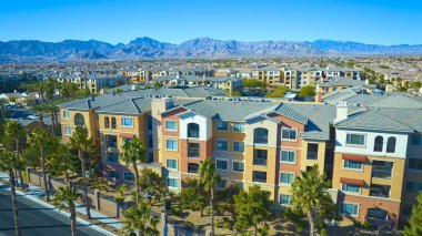 Toprak tonlu daireleri ve palmiye kaplı caddeleri olan modern Las Vegas 'ın hava manzarası. Görkemli dağlara karşı kurulmuş ve açık mavi gökyüzü çöl şehrinde kentsel ahengi gözler önüne seriyor..