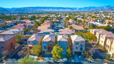 Las Vegas, Nevada 'da yoğun bir banliyö mahallesinin hava görüntüsü. Çamurla kaplı çatılar ve güneşli bir gökyüzünün altında dar sokaklar görkemli bir dağ zeminiyle yaşayan şehirlileri harmanlıyor..