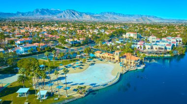 Güneşli bir Las Vegas banliyösünün havadan görünüşü palmiye ağaçları ve kumlu plajlı bir rıhtım parkını gösteriyor. Terra-cotta çatıları ve yemyeşil alanlar dağlık bir zemin ile sakin bir kaçış yaratır..