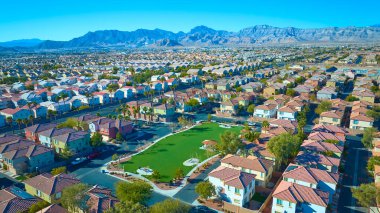 Las Vegas 'ın sakin bir banliyösünün havadan görünüşü toprak tonlu evler, palmiye çizgili sokaklar ve canlı bir park, hepsi görkemli bir dağ zeminine karşı kurulmuş, çölde yaşayan.