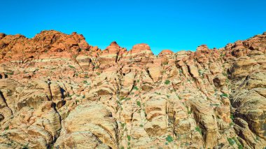 Nevada Red Rock Kanyonu 'nun nefes kesici güzelliğini keşfedin. Açık mavi gökyüzü altındaki engebeli kırmızı kumtaşı oluşumlarına hayret, macera ve keşif temaları için mükemmel..