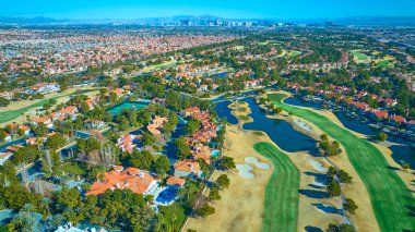 Önünde yemyeşil bir golf sahası olan Las Vegas banliyösünün havadan görünüşü. Terracotta-çatı evler yeşil ortamda yuva, canlı şehir silueti resim arkaplan olarak gökyüzü.
