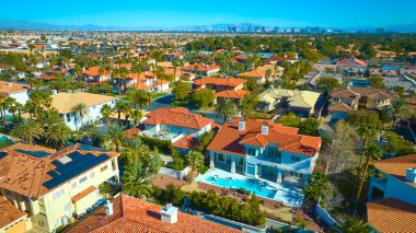 Akdeniz tarzı evleri olan canlı bir Las Vegas banliyösünün havadan görünüşü. Palmiye ağaçları ve açık mavi gökyüzü çöl manzarasını ön plana çıkararak sakinliği kentsel yakınlıkla harmanlıyor. Gerçekten ideal.