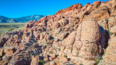 Las Vegas yakınlarındaki Calico 'da Kızıl Kaya Kanyonu' nun canlı kumtaşı oluşumlarının havadan görüntüsü. Parlak mavi gökyüzüne karşı kırmızı renklerin çarpıcı kontrastını deneyimleyin. Doğanın güzelliğinin çarpıcı bir kanıtı..