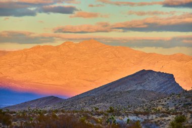 Günbatımı Nevada 'da Charleston Dağı' nda sıcak bir ışıltıyla yıkanır. Engebeli dağlar ve çöl bitkileri seyahat ve doğa projeleri için mükemmel sakin bir manzara yaratır. Las Vegas yakınlarında sakin bir kaçış..